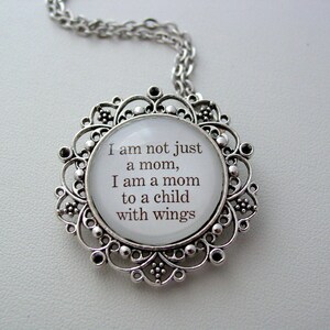 May include: Silver necklace with a round pendant featuring a white background and the text "I am not just a mom, I am a mom to a child with wings."