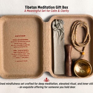 May include: A Tibetan Meditation Gift Box set in a natural-toned container. The set includes a prayer bead necklace, a carved stone, a wooden item, and a brass bowl. Text on the box reads "A Meaningful Set for Calm & Clarity."