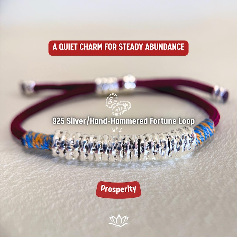 May include: A burgundy and silver bracelet with the text "925 Silver/Hand-Hammered Fortune Loop." The bracelet features a silver central section and blue and orange accents. The text "A Quiet Charm for Steady Abundance" and "Prosperity" are also present.