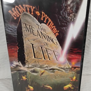 May include: A DVD case for Monty Python's The Meaning of Life featuring a large stone tablet rising from water with a lightning bolt striking it. The cover includes the film title and the names of the cast members in a dark, dramatic setting.