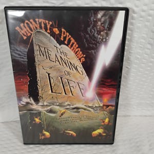 May include: A DVD case for "Monty Python's The Meaning of Life" features a tombstone design with the title text. The cover art includes a lightning bolt, water, and fish. The case is black.
