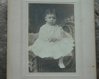 Precious vintage parlor photo of small child on rattan chair