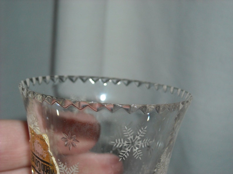 K&ouml;nnte beinhalten: Nahaufnahme einer durchsichtigen Glasglocke mit einem gewellten Rand und ge&auml;tzten Schneeflockenmustern. Die Glocke hat ein kleines Papieretikett mit dem Text "Webb Co."