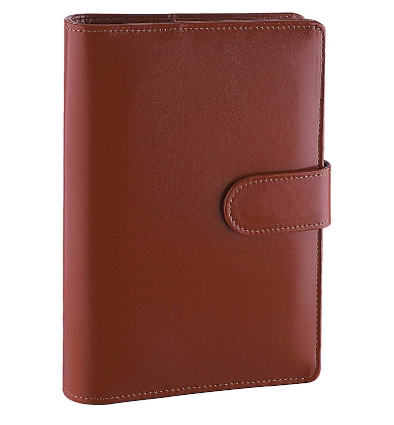 May include: A brown leather bound planner with a flap closure and a stitched design.