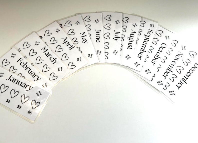 May include: Twelve white cards with black hearts and the months of the year written in black text. Each card has a different month written on it, starting with January and ending with December. The cards are arranged in a semi-circle, with the January card at the bottom and the December card at the top.