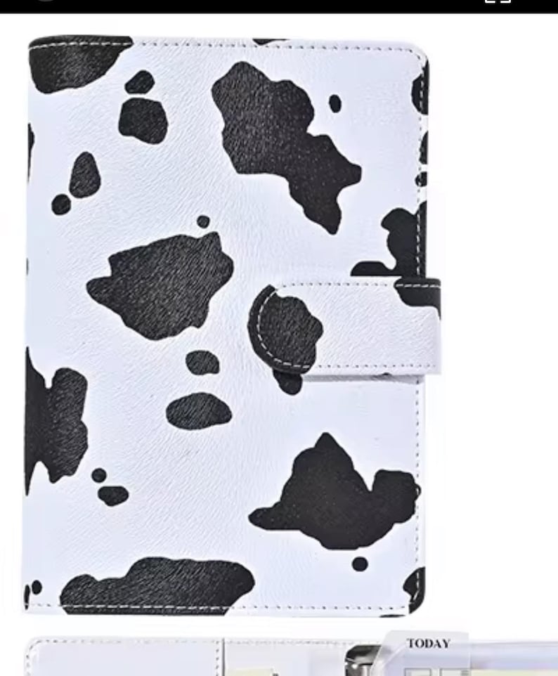 May include: A white planner featuring a black cow print design. The planner has a flap closure with a press stud. It is designed to hold inserts and has a tabbed section at the bottom. A stylish way to stay organised.