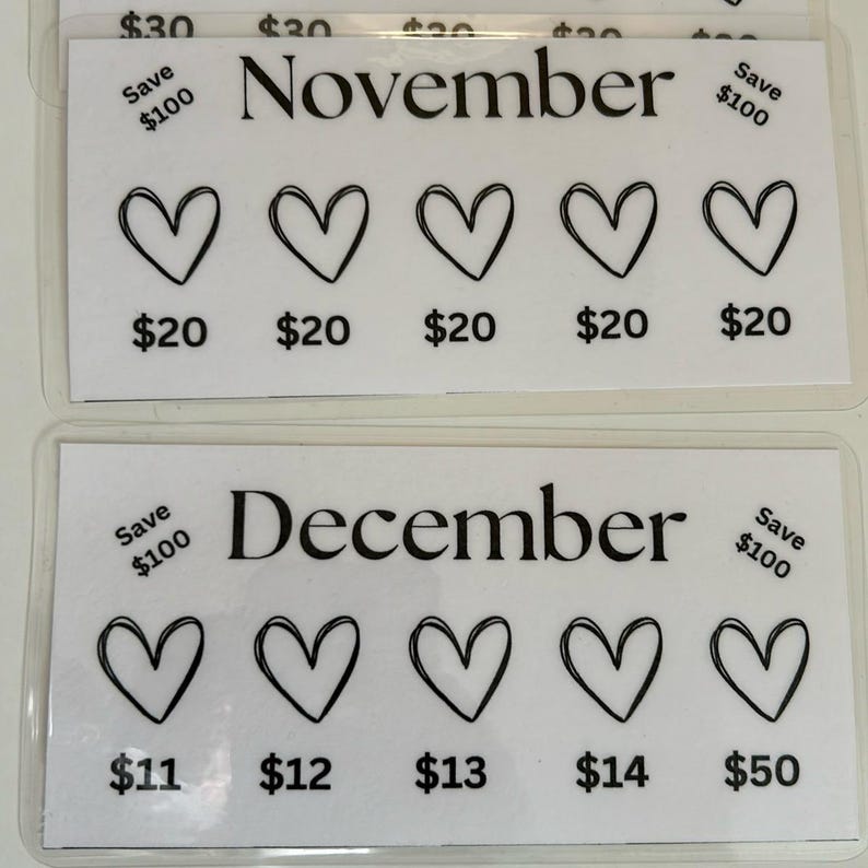 May include: Two white cards with black text and hearts. The top card says "November" and has five hearts with prices of $20 and a "Save $100" note. The bottom card says "December" and has five hearts with prices of $11, $12, $13, $14, and $50 and a "Save $100" note.