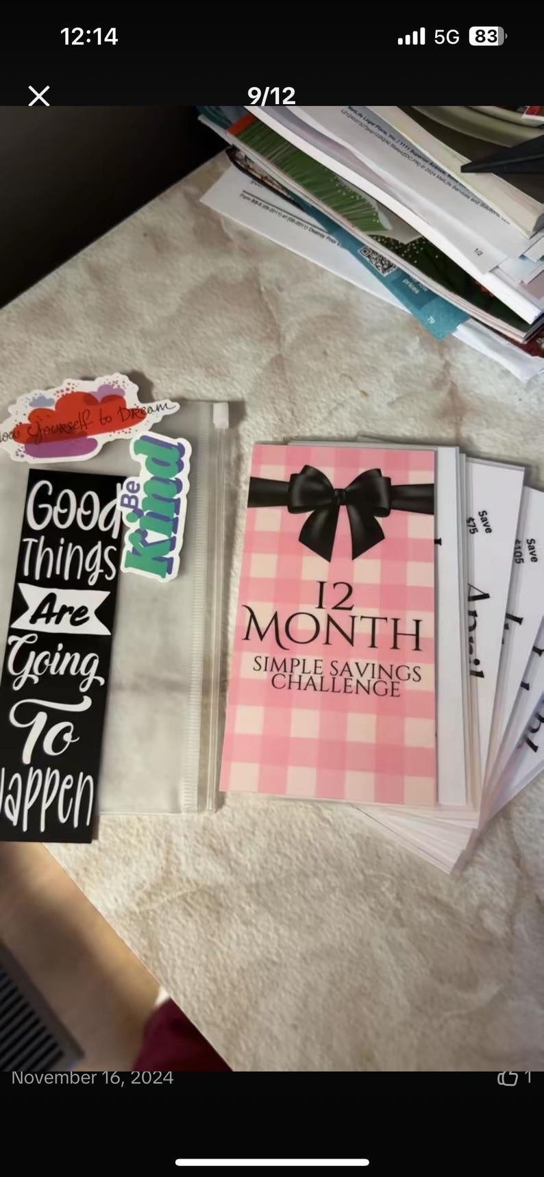 May include: A pink and white checkered card with a black bow and the text "12 Month Simple Savings Challenge". The card is part of a stack of cards with the text "Save $75" and "Save $105" visible.