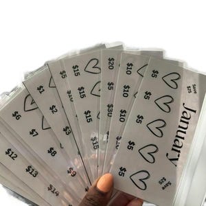 May include: A stack of white gift cards with a heart design and the text "January" and "Save $25" on the top card. The cards have different dollar amounts printed on them, ranging from $1 to $20.
