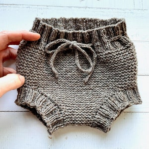 May include: Brown knitted baby bloomers with a drawstring tie at the waist.