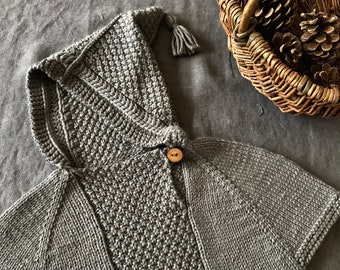 May include: A gray hooded knitted cape with a wooden button and a tassel on the hood.