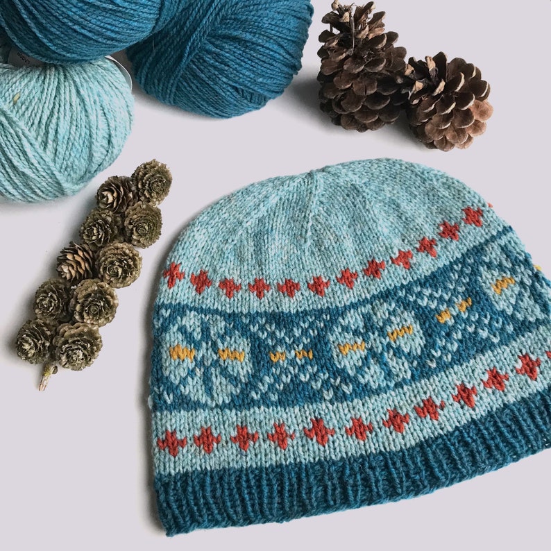 May include: A blue and teal knitted hat with a geometric pattern in red, yellow, and white. The hat is made with a soft, textured yarn.