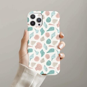 May include: A white iPhone case featuring a pattern of seashells in shades of blue, pink, and white.