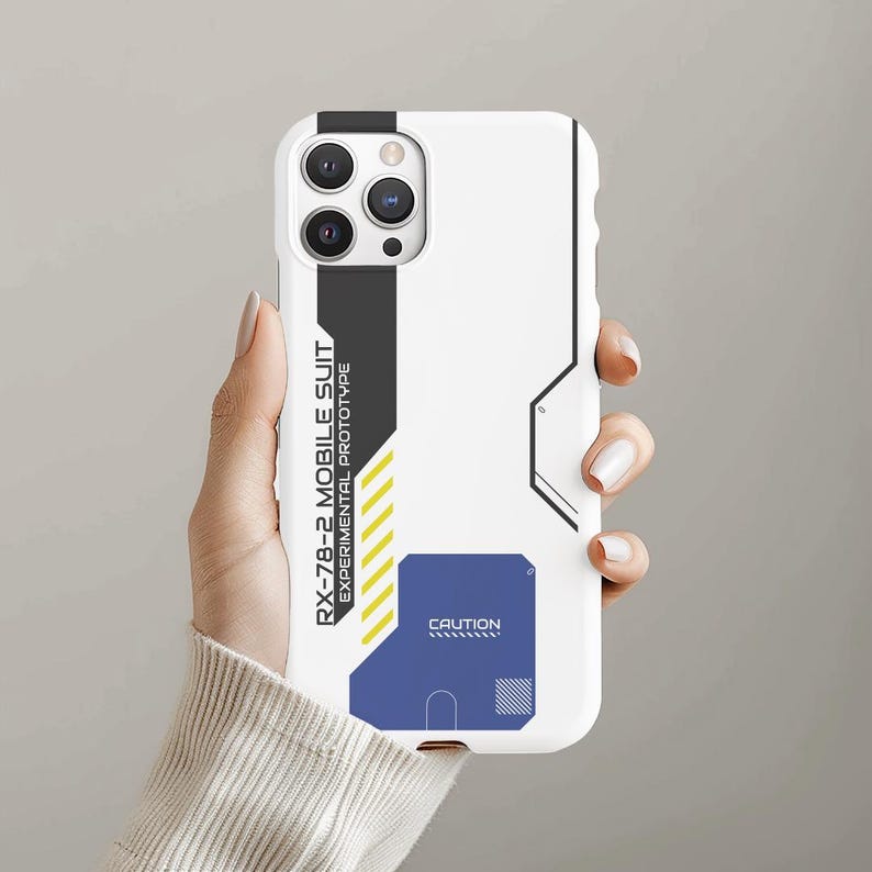 May include: White phone case with a black and yellow design. The case has a camera lens cutout and the text "RX-78-2 MOBILE SUIT EXPERIMENTAL PROTOTYPE" and "CAUTION".