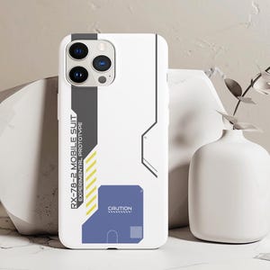 May include: White phone case with a black and gray design. The case has a graphic of a robot with the text "RX-78-2 MOBILE SUIT EXPERIMENTAL PROTOTYPE" and "CAUTION".