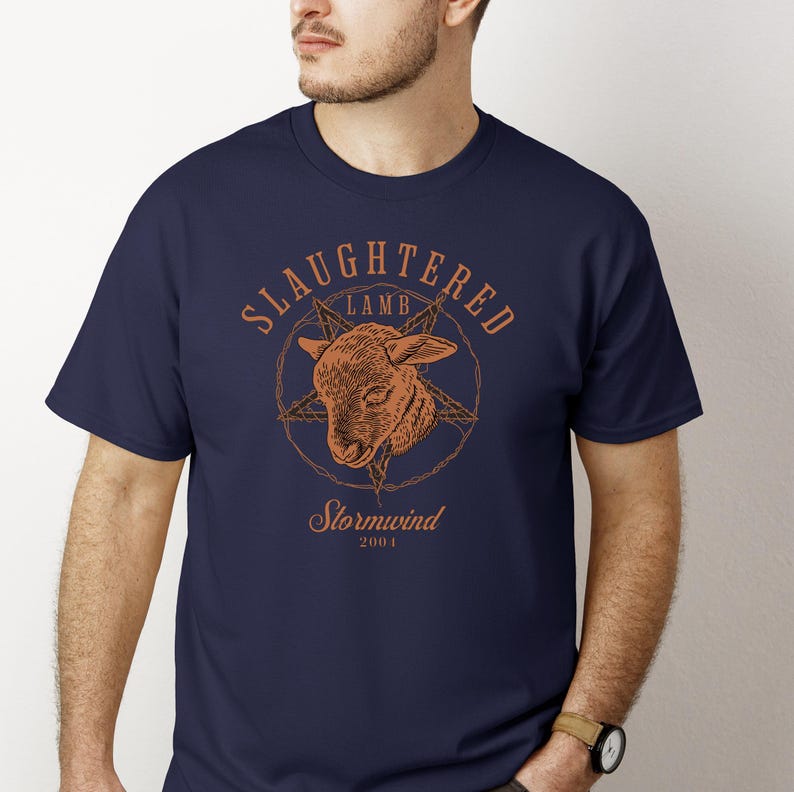 May include: Navy blue t-shirt with a distressed orange graphic. The graphic features a lamb's head inside a pentagram, with the words "SLaughtered Lamb" above and "Stormwind 2001" below. The shirt is a crew neck.