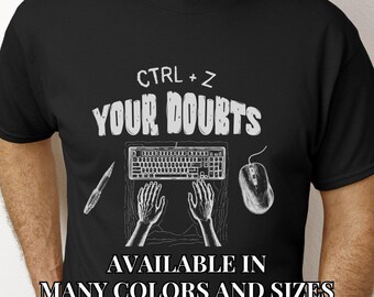 May include: Black t-shirt with white text that reads "CTRL + Z YOUR DOUBTS". The shirt also features a keyboard, mouse, and two hands typing. The text "AVAILABLE IN MANY COLORS AND SIZES" is at the bottom of the shirt.