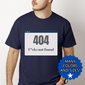 May include: Navy blue t-shirt with a graphic of a 404 error message and the text "F*cks not found". The design is inside a computer window. A blue starburst graphic with the text "MANY COLORS AND SIZES!" is in the lower right corner.