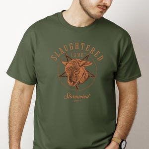 May include: Olive green t-shirt featuring a detailed illustration of a lamb's head within a star, with the words "SLaughtered Lamb" above and "Stormwind 2001" below in a rustic font.
