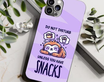 May include: Purple phone case featuring a cartoon sloth sleeping with a thought bubble that reads "Do Not Disturb Unless You Have Snacks".