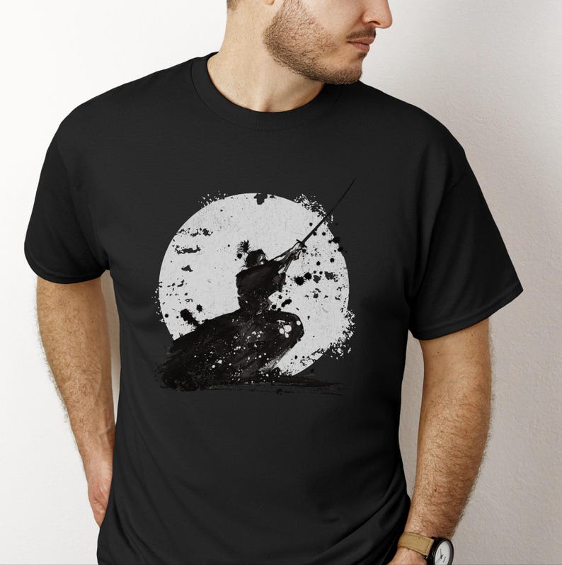 K&ouml;nnte beinhalten: Schwarzes T-Shirt mit einer schwarz-wei&szlig;en Grafik eines Samurai-Kriegers vor einem wei&szlig;en Kreis, der an einen Mond erinnert. Der Samurai ist mit einem Schwert dargestellt. Das Design ist in Schwarz und Wei&szlig; gehalten.