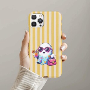 May include: A phone case with a yellow and white striped pattern. The case features a cartoon ghost wearing pink sunglasses and holding a cocktail. The ghost also carries a pink handbag. The case is designed for a smartphone.
