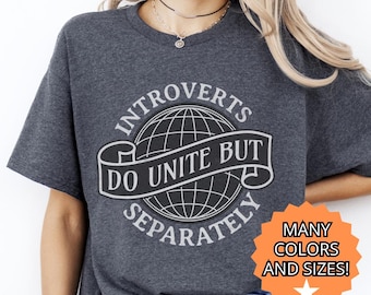 Może przedstawiać: Ciemnoszara koszulka z białym nadrukiem. Nadruk zawiera napis "Introverts Do Unite But Separately" wokół globu. Gwiazda mówi "Many Colors and Sizes!"