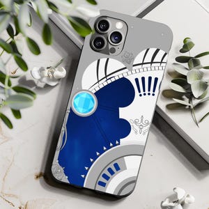 Könnte beinhalten: Eine weiße und blaue Handyhülle mit geometrischem Design. Die Hülle verfügt über einen blauen Edelstein und ein weiß-schwarzes Muster.