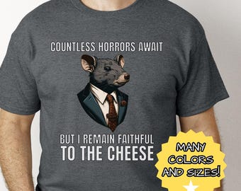 May include: A dark gray t-shirt with a cartoon rat wearing a suit and tie. The text on the shirt reads "Countless horrors await but I remain faithful to the cheese". The bottom right corner of the image has a yellow star and the text "Many colors and sizes!"