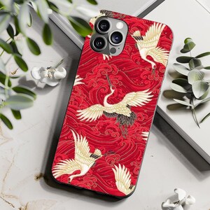 May include: A red iPhone case with a white and black crane design. The case features a wave pattern and a red background.