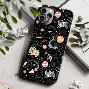 May include: Black phone case featuring a space-themed design with planets, stars, rockets, and cartoon animals in astronaut helmets. The case has a glossy finish and is designed to fit a smartphone.