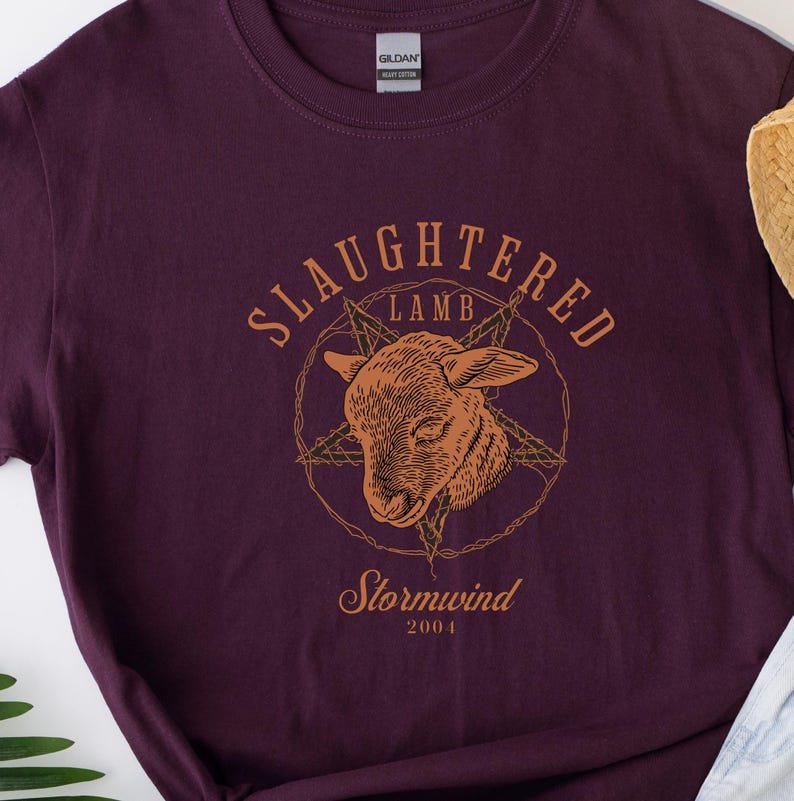 May include: Dark purple t-shirt with a graphic of a lamb's head inside a star and circle, with the words "SLaughtered Lamb" above and "Stormwind 2004" below in a serif font. The shirt is made of heavy cotton.