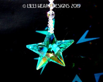 May include: A teal blue crystal star hanging from a clear crystal chain. The star is faceted and reflects light.