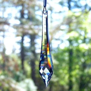 May include: A long, teardrop-shaped crystal prism with a faceted design. The prism is iridescent, reflecting rainbow colors.