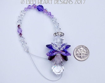 May include: Purple and clear crystal angel car charm with a silver metal ring and a clear crystal teardrop pendant.  The charm is hanging from a silver chain with clear and purple crystals.  The charm is about the size of a US dime.
