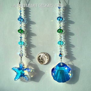 May include: Two beaded suncatchers with a starfish and seashell charm. The suncatchers have blue, green, and clear beads. The charms are iridescent blue. A US quarter is next to the suncatchers.