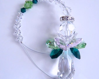 May include: A crystal angel suncatcher with clear, green, and pink crystals. The angel has a silver ring with clear crystals around its neck. The suncatcher is hanging from a clear string.