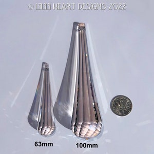 May include: Two clear crystal teardrop prisms, one measuring 63mm and the other 100mm. The prisms have a faceted design and are shown against a white background.