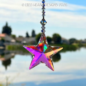 May include: A faceted crystal star suncatcher with an iridescent finish that reflects rainbow colors. The star hangs from a vertical strand of smaller clear crystal beads. The text LILLI HEART DESIGNS 2026 is visible at the top of the image.