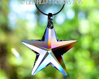 May include: A silver chain necklace with a large iridescent crystal star pendant. The star is faceted and reflects light in rainbow colours.