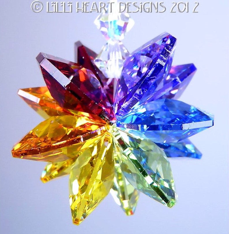 Puede incluir: Un atrapasol de cristal arco&iacute;ris con un dise&ntilde;o de estrella. El cristal est&aacute; formado por ocho puntas, cada una de un color diferente del arco&iacute;ris. El cristal est&aacute; colgado de una cuerda transparente.