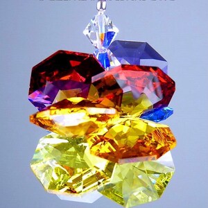 Puede incluir: Un atrapasol de cristal con un arco&iacute;ris de colores, incluyendo rojo, naranja, amarillo, verde, azul y morado. Los cristales son facetados y brillan a la luz.