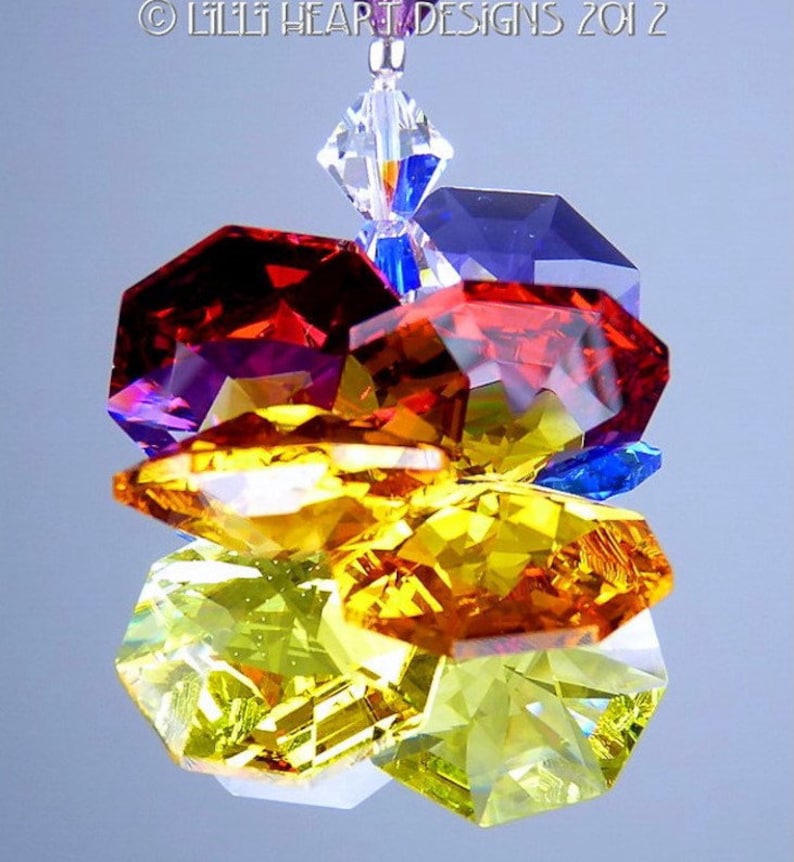 Puede incluir: Un atrapasol de cristal con un arco&iacute;ris de colores, incluyendo rojo, naranja, amarillo, verde, azul y morado. Los cristales son facetados y brillan a la luz.