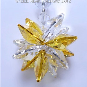May include: A crystal suncatcher with a starburst design. The starburst is made of clear and amber crystals.