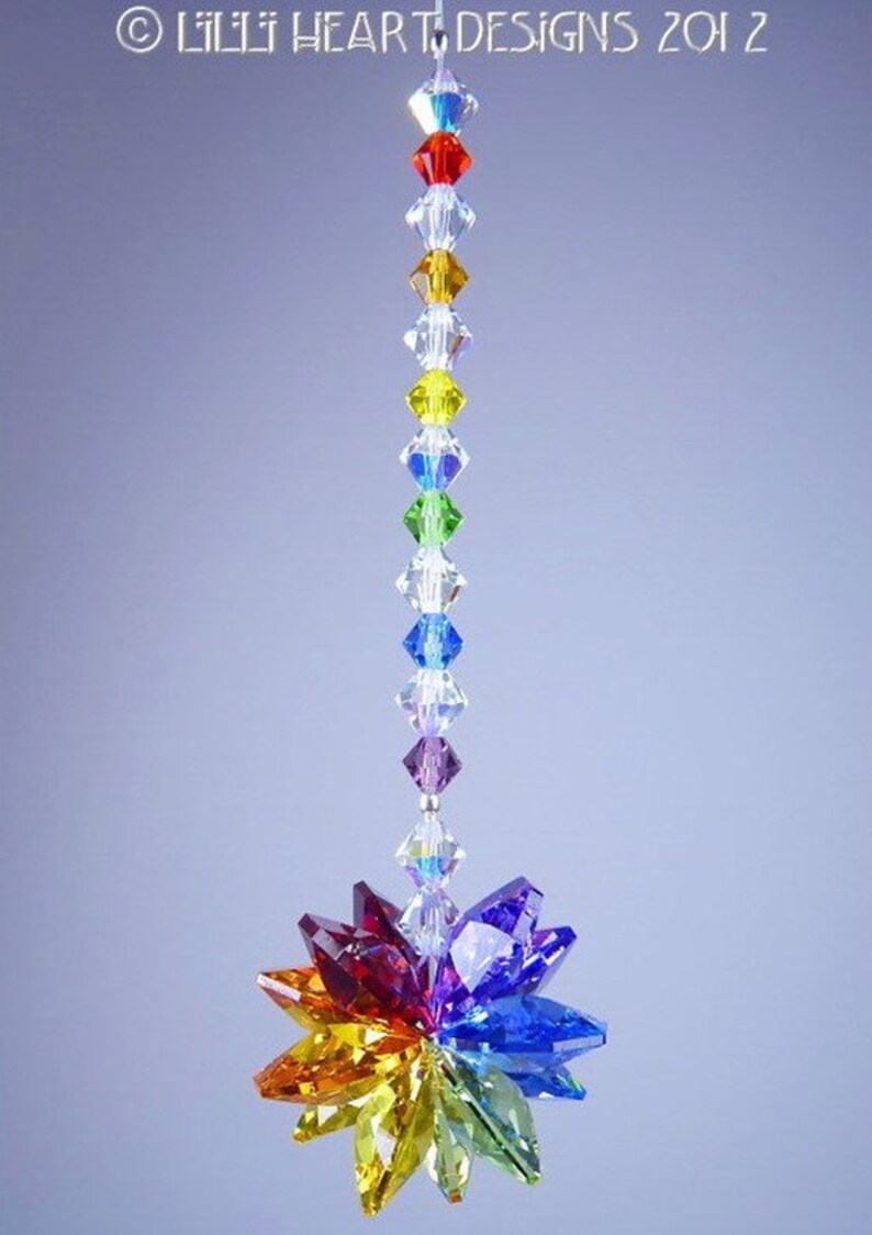 Puede incluir: Un atrapasol de cristal arco&iacute;ris con una cadena de cristal colgando de la parte superior. El atrapasol est&aacute; hecho de cristales facetados en tonos de rojo, naranja, amarillo, verde, azul, &iacute;ndigo y violeta.