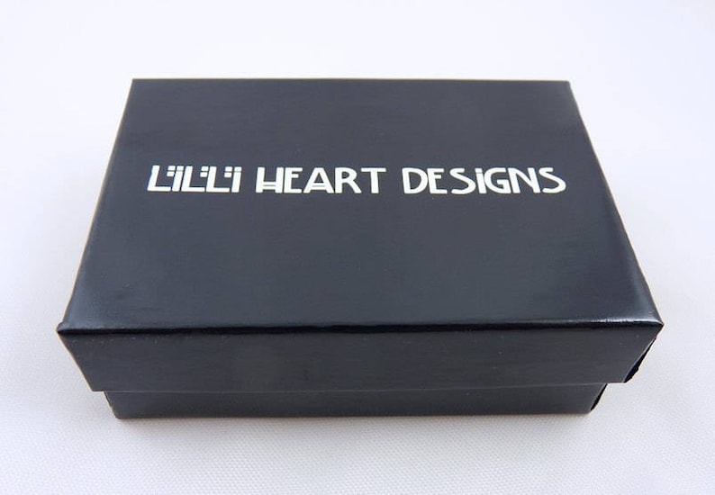 May include: A black box with the text "Lilli Heart Designs" printed in white on the top.