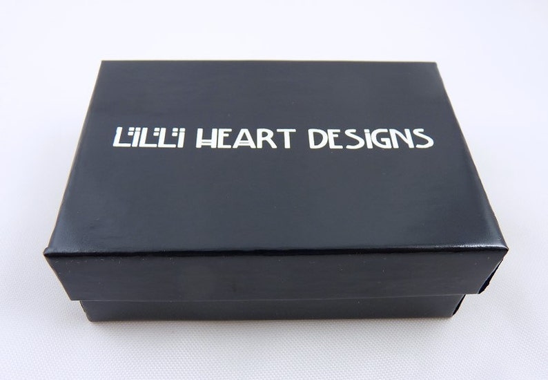 May include: A black box with the text "Lilli Heart Designs" printed in white on the top.