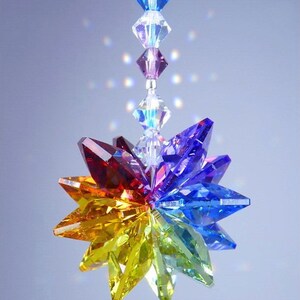 Puede incluir: Un atrapasol de cristal arco&iacute;ris con un dise&ntilde;o de estrella. El atrapasol est&aacute; hecho de cristales facetados en tonos de rojo, naranja, amarillo, verde, azul, &iacute;ndigo y violeta. El atrapasol est&aacute; suspendido de una cadena plateada.
