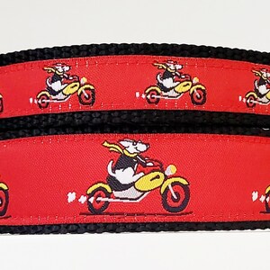 May include: Red dog collar with a black border and a repeating pattern of white dogs riding yellow motorcycles.