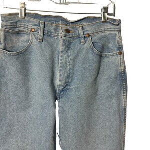 May include: Light blue denim jeans with a classic five-pocket style. The jeans have a straight leg and a button fly.